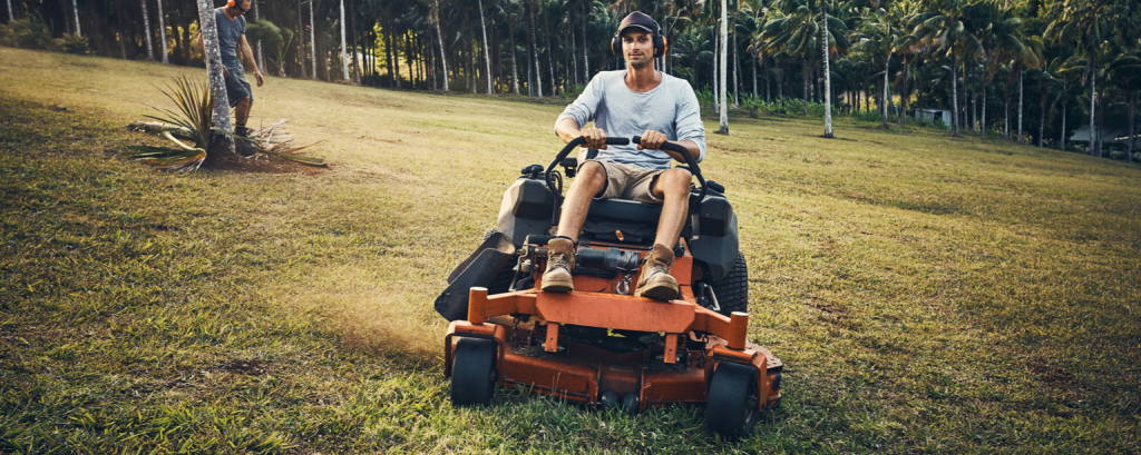 Lawn care worker mows grass