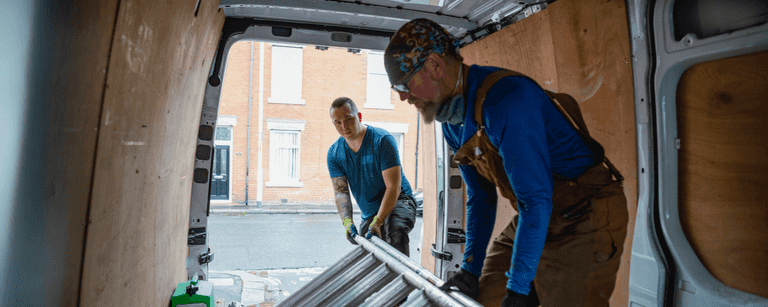 Two male workers inside of a van unloading and delivering goods