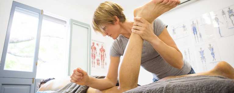 Massage therapist moving client's knee