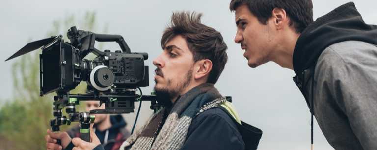 Director holding camera alongside film crew