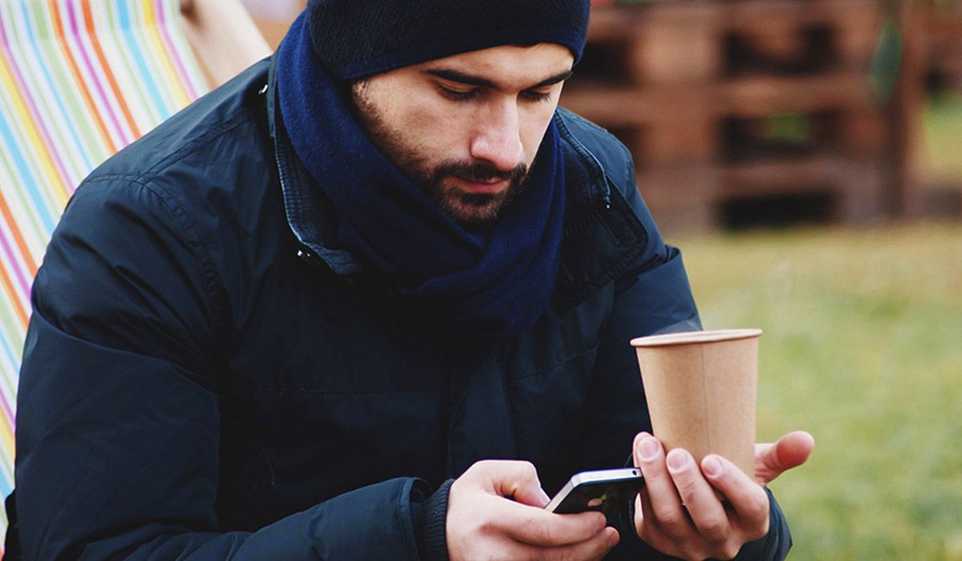 Man sits on a bench outdoors with a cup of coffee wondering how to get overdue invoices paid.