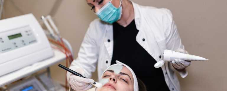 A licensed esthetician applying a face mask on her client