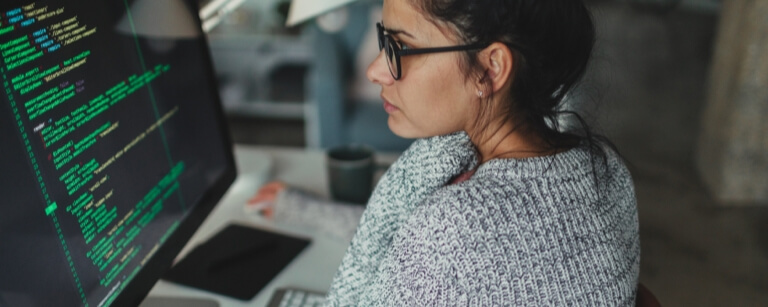 Female app developer reviews code on desktop