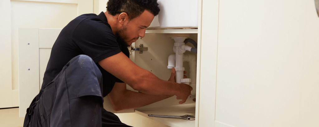 man working under a kitchen sink