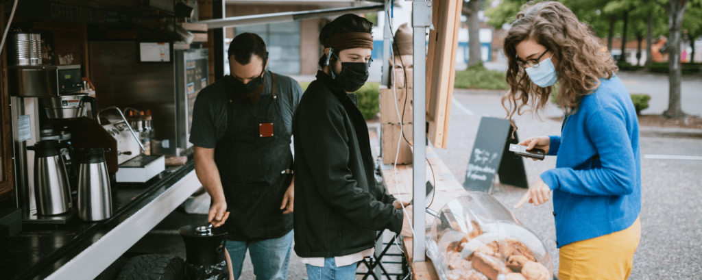 Woman wearing mask making purchase at a food truck