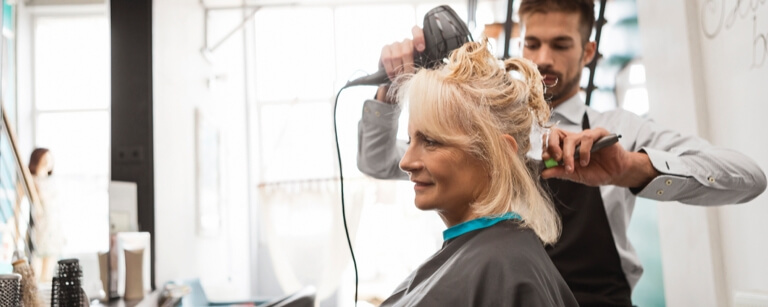 An insured Male hairdresser works with client at hair salon