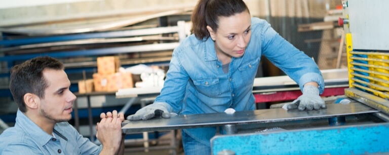 Two sheet metal workers using press