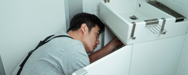 A plumber with plumbing insurance fixing a kitchen sink