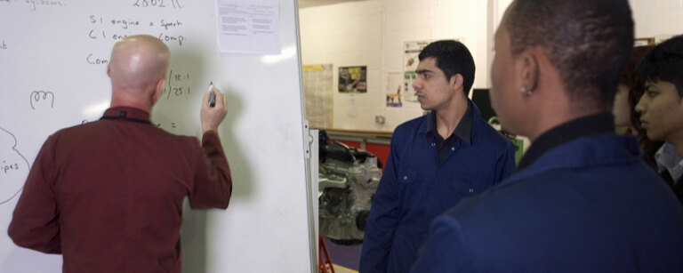 Project manager meeting with group at whiteboard