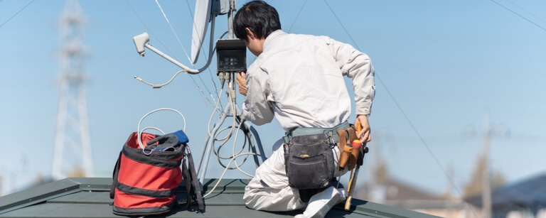 TV satellite installer working on flat roof top