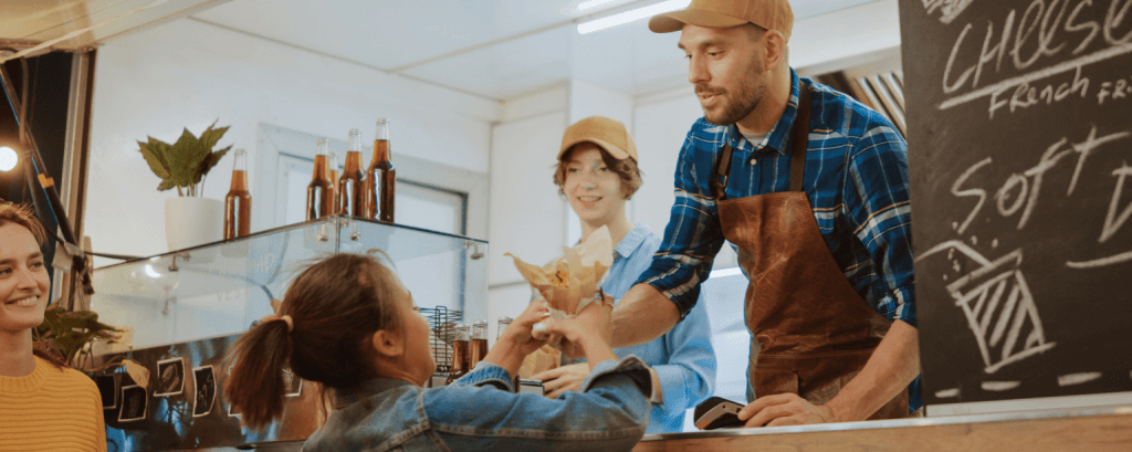 Ice cream shop clerk hands ice cream to child