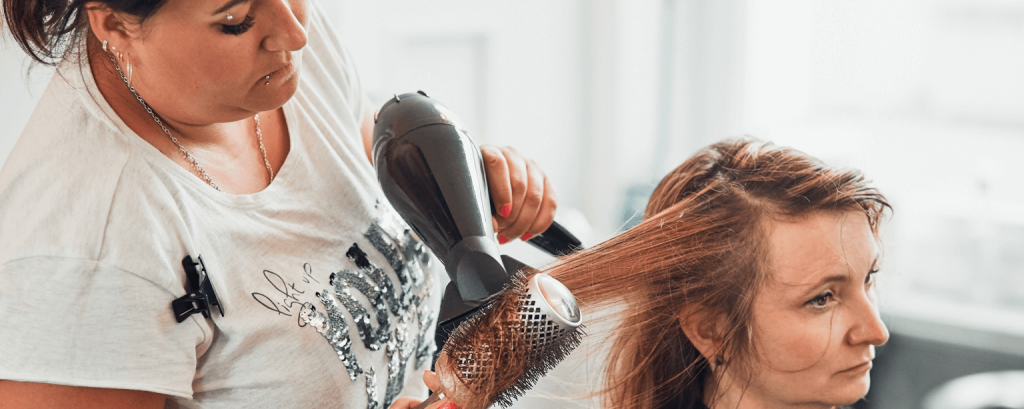 Hairdresser blowdries client's hair
