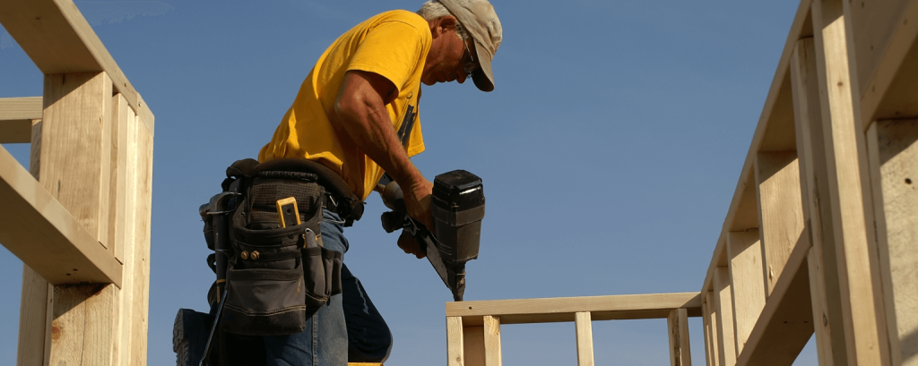 Builder uses nail gun on framing