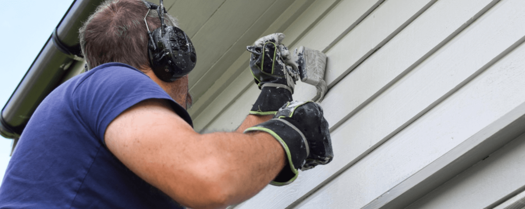 Painter works on exterior of house
