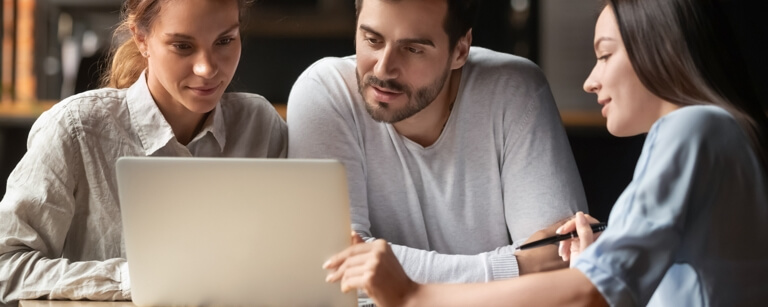 A travel agent working with a couple at a laptop