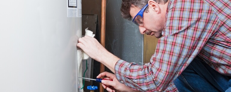 Water treatment technician uses screwdriver to fix system