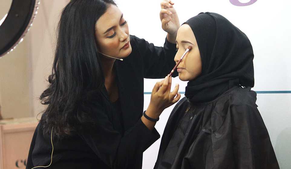 Learn how to become a makeup artist, like this woman applying makeup to her client.