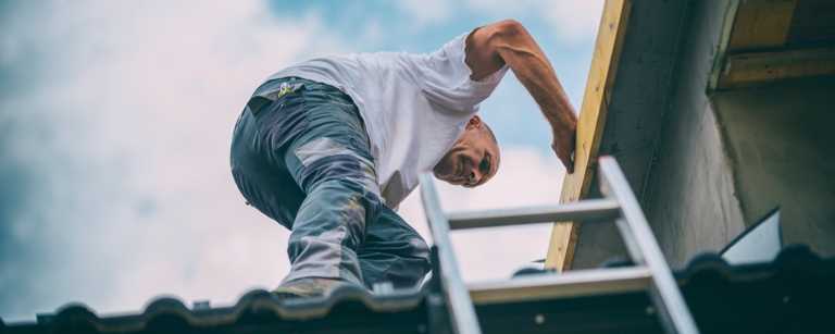 A roofer climbing down a ladder