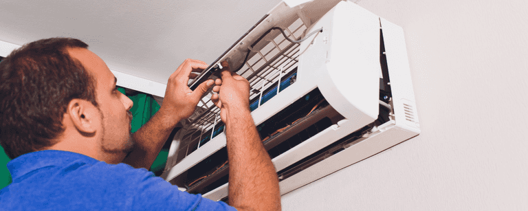 HVAC technician works on AC unit