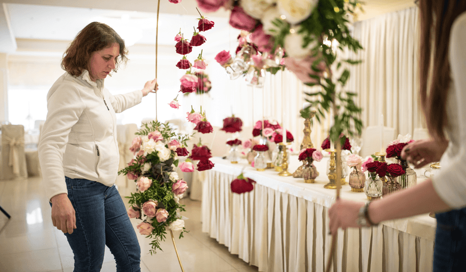 A female party planner is inspecting floral decorations at a party.
