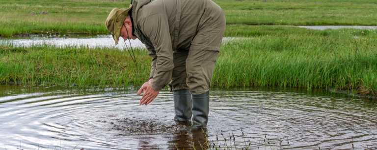 Man checks water in field