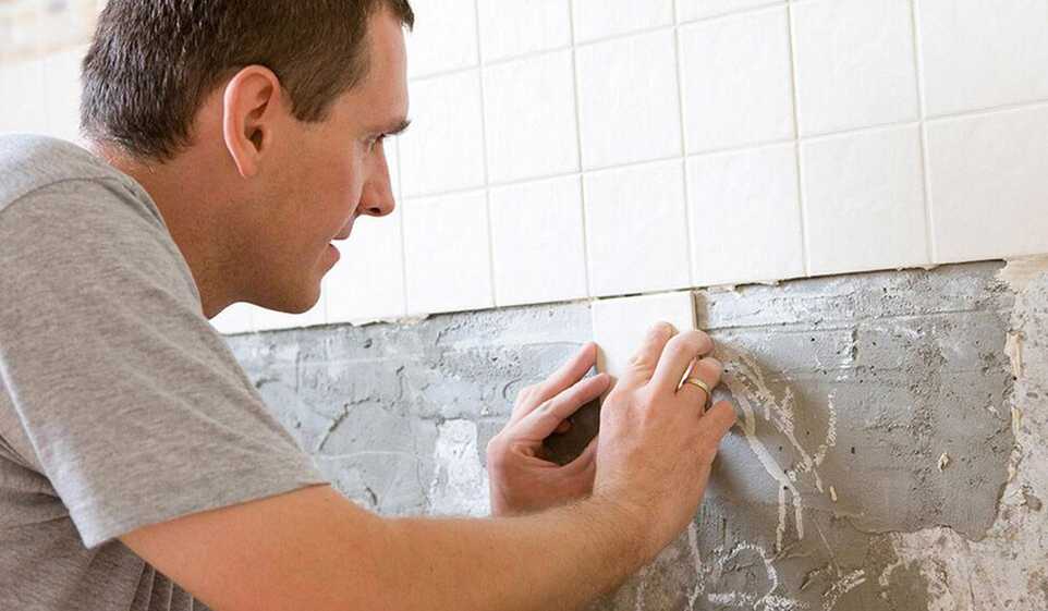 A man learned how to start a handyman business and is installing tiles in a bathroom