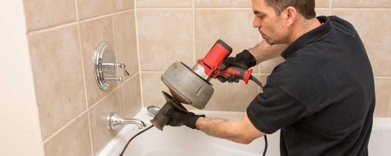 A plumber unclogging a shower drain