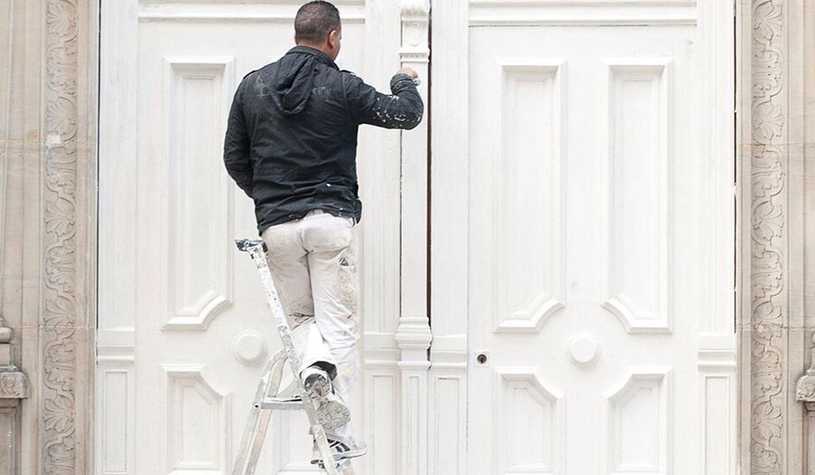 Painters insurance can keep you protected while you work on ladders, like this professional painter.