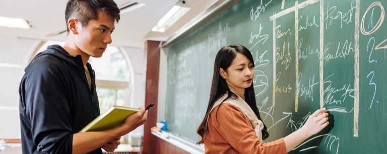 Tutor teaching student at chalk board