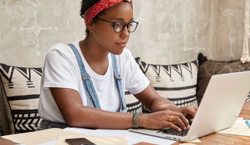 Woman with red bandana and glasses typing on a laptop computer