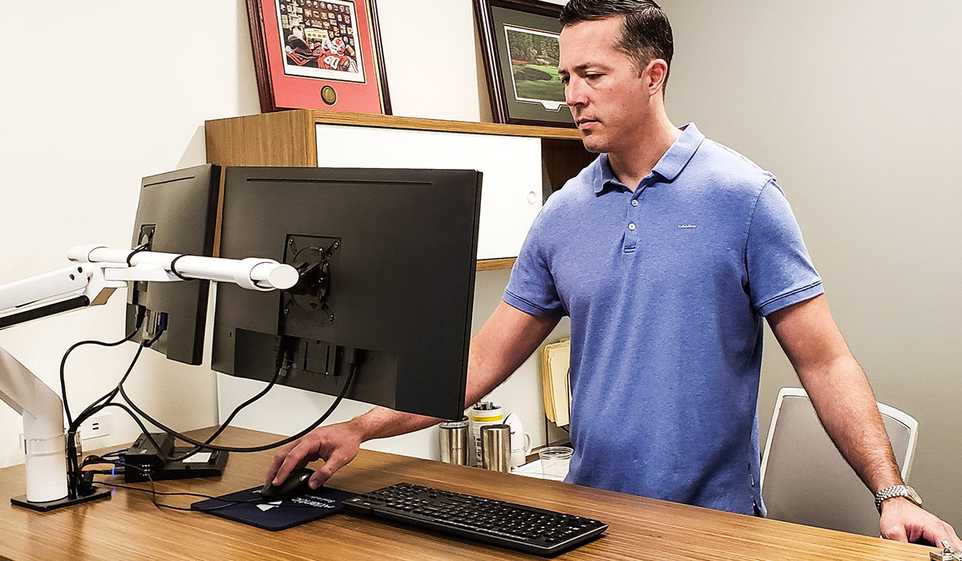 Going from your full-time job to owning a business can be challenging, but you can do it, like this entrepreneur at his standing desk.