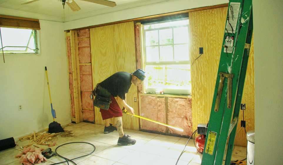 A contractor repairs wall damage from a storm.