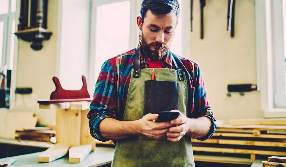 Once you’re ready for small business insurance, find a provider that lets you compare policies, like this business owner on his phone.