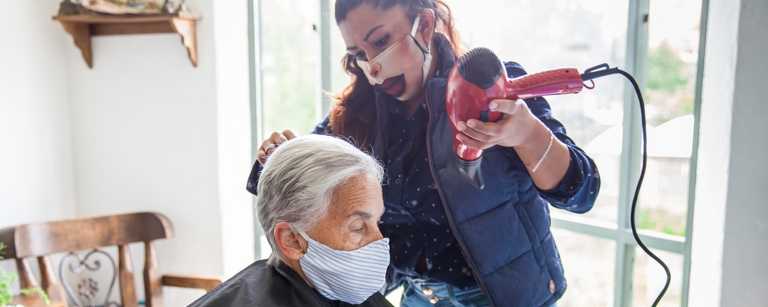 Mobile hairdresser cuts elderly woman's hair