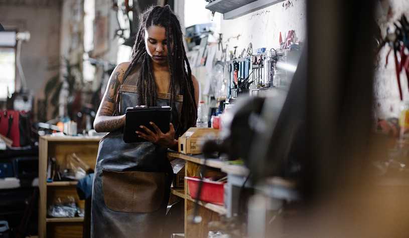 Woman wearing metal workers apron working on an iPad.