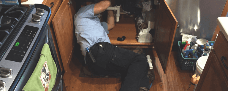 Plumber works under sink