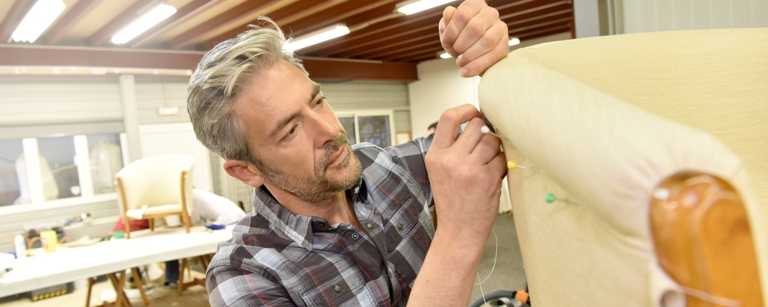 Upholsterer pushes pins into a chair