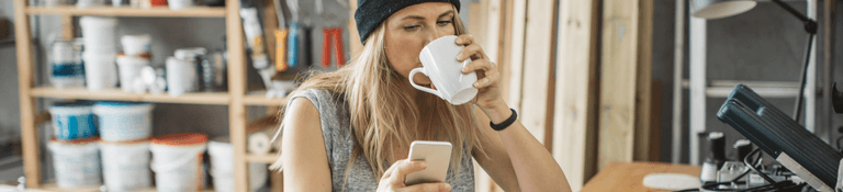 woman drinking coffee looking at phone