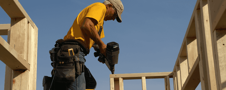 Builder uses nail gun on framing