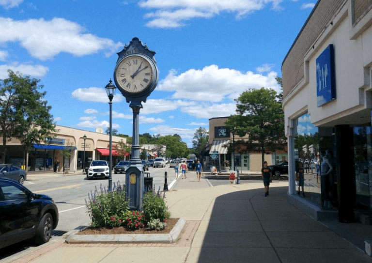 view of main street in Massachusetts with a large clock on the sidewalk
