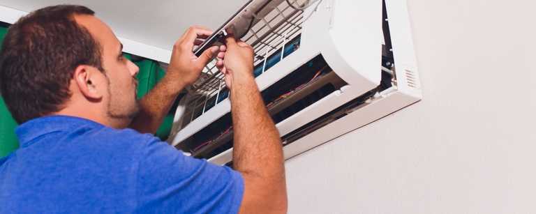 HVAC technician repairing residential AC unit indoors
