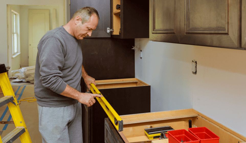 A man used a level to check the installation of a cabinet.