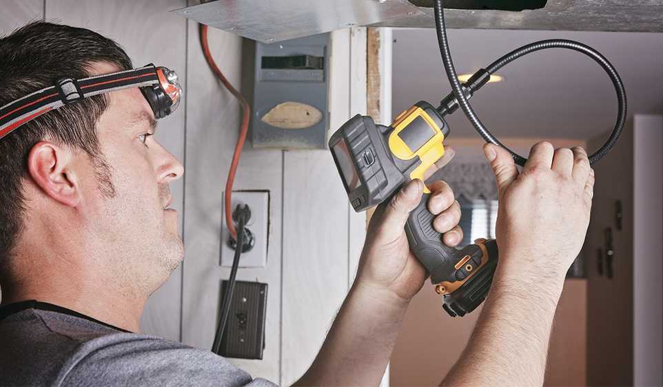 man with head lamp using inspection camera on ceiling