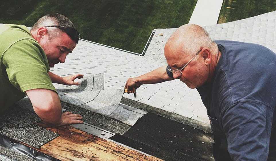 Two male contractors who have their Arkansas contractors license are installing panels on a roof