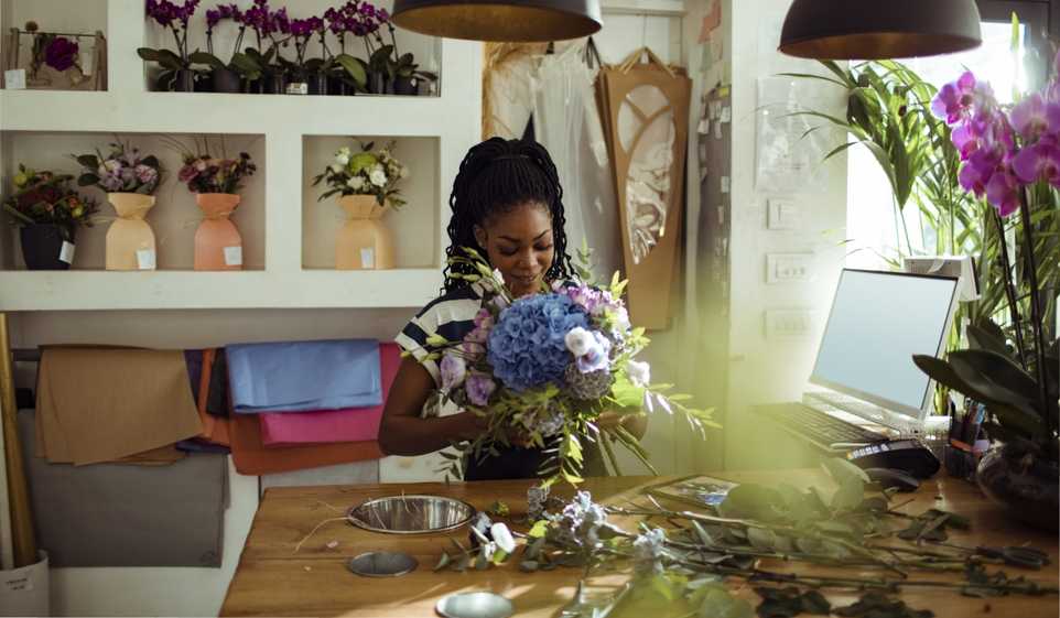 A florist arranges a flower bouquet on a table.
