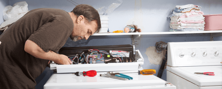 Appliance repair tech works on washing machine
