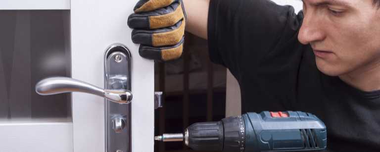 A locksmith uses a drill to install a lock