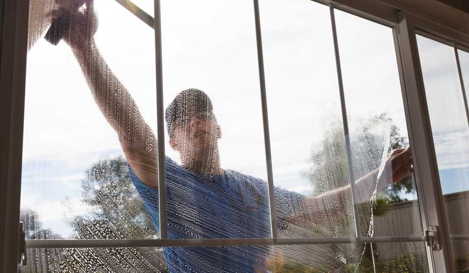 A window washer with a South Dakota business license cleans a customer's window.