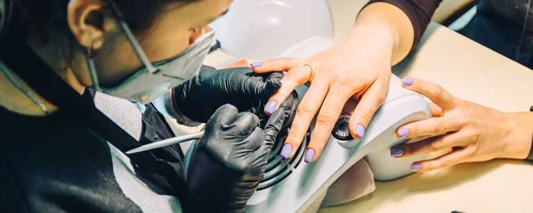Close-up of nail technician working with client using brush