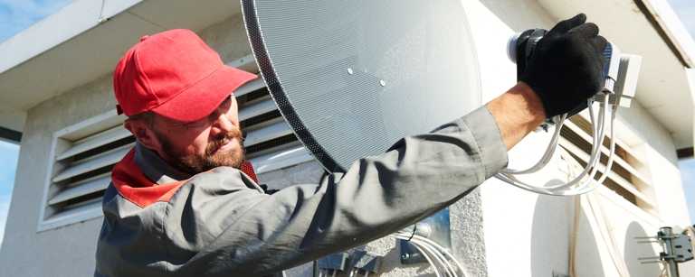 TV satellite installer adjusting direction of dish